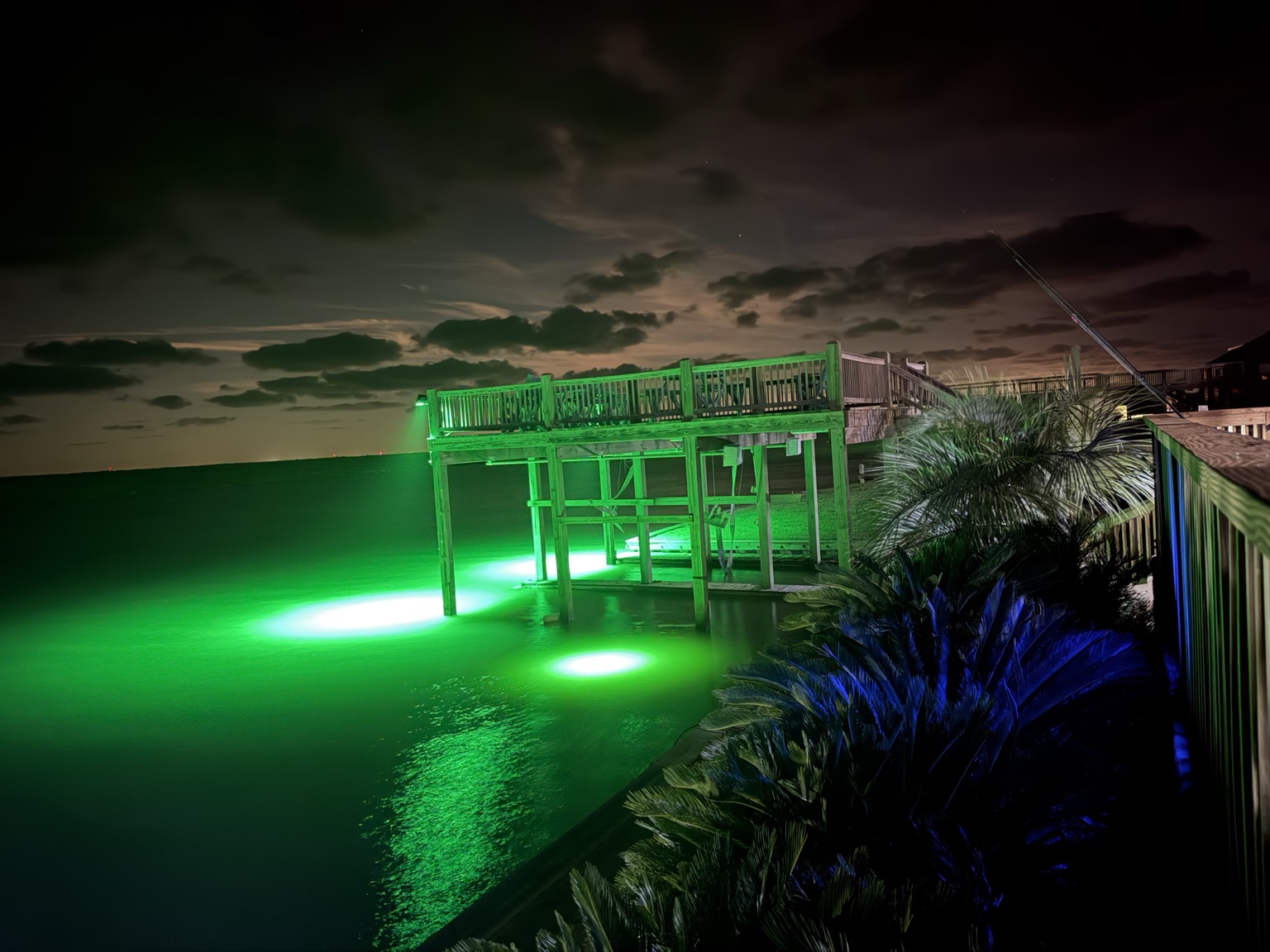 Upper boathouse deck and green fishing lights over the water at night