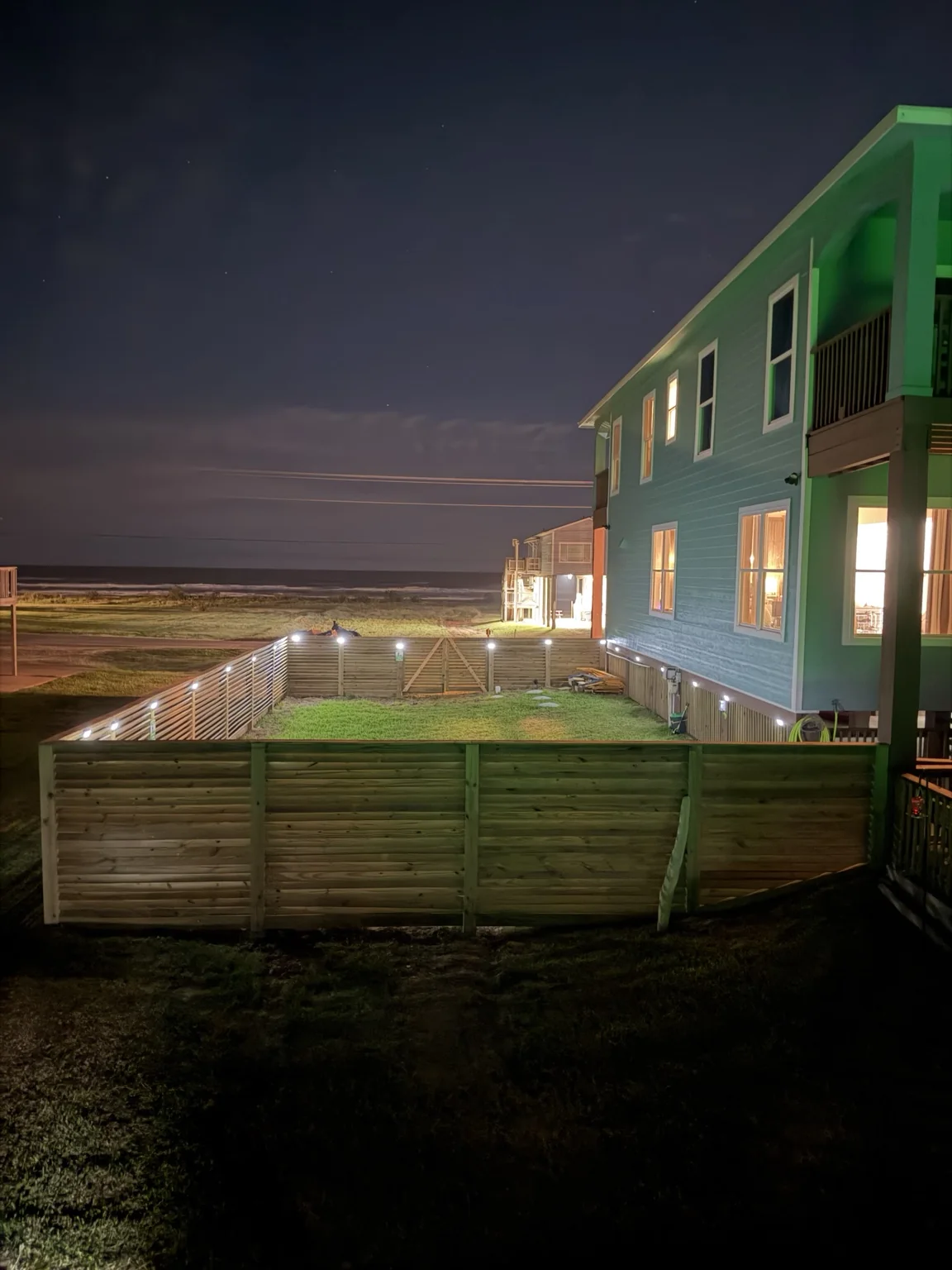 Fenced and illuminated dog area beside Ace in the Hole Lodge at night